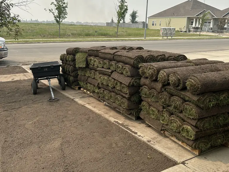 Pallets of fresh sod stacked on a driveway ready for install